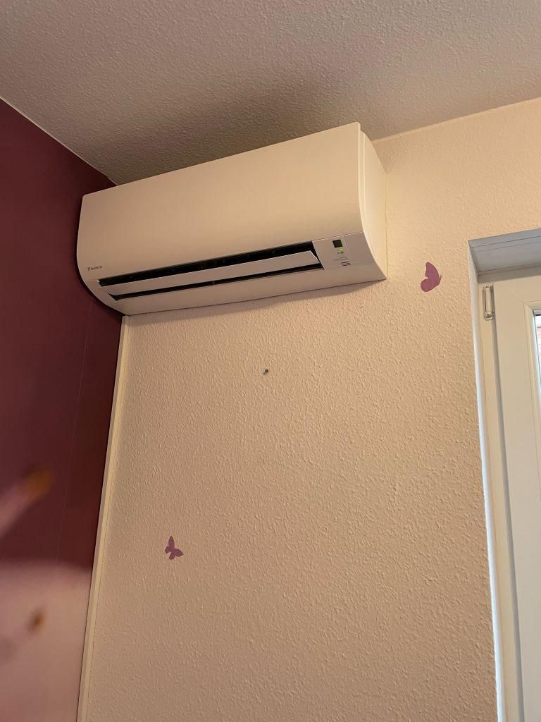Eine weiße Klimaanlage ist an einer Wand neben einem Fenster montiert