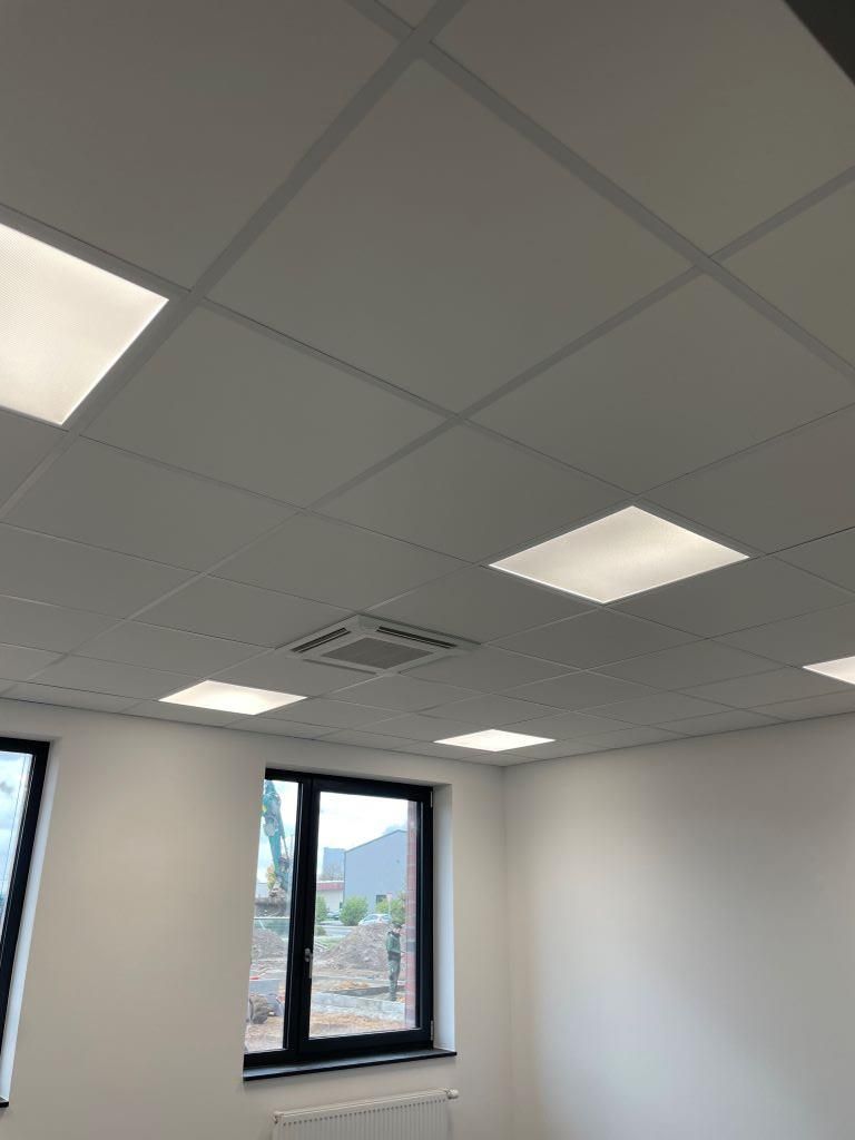 Ein Raum mit einer Decke mit quadratischen Lichtern und einem Fenster.