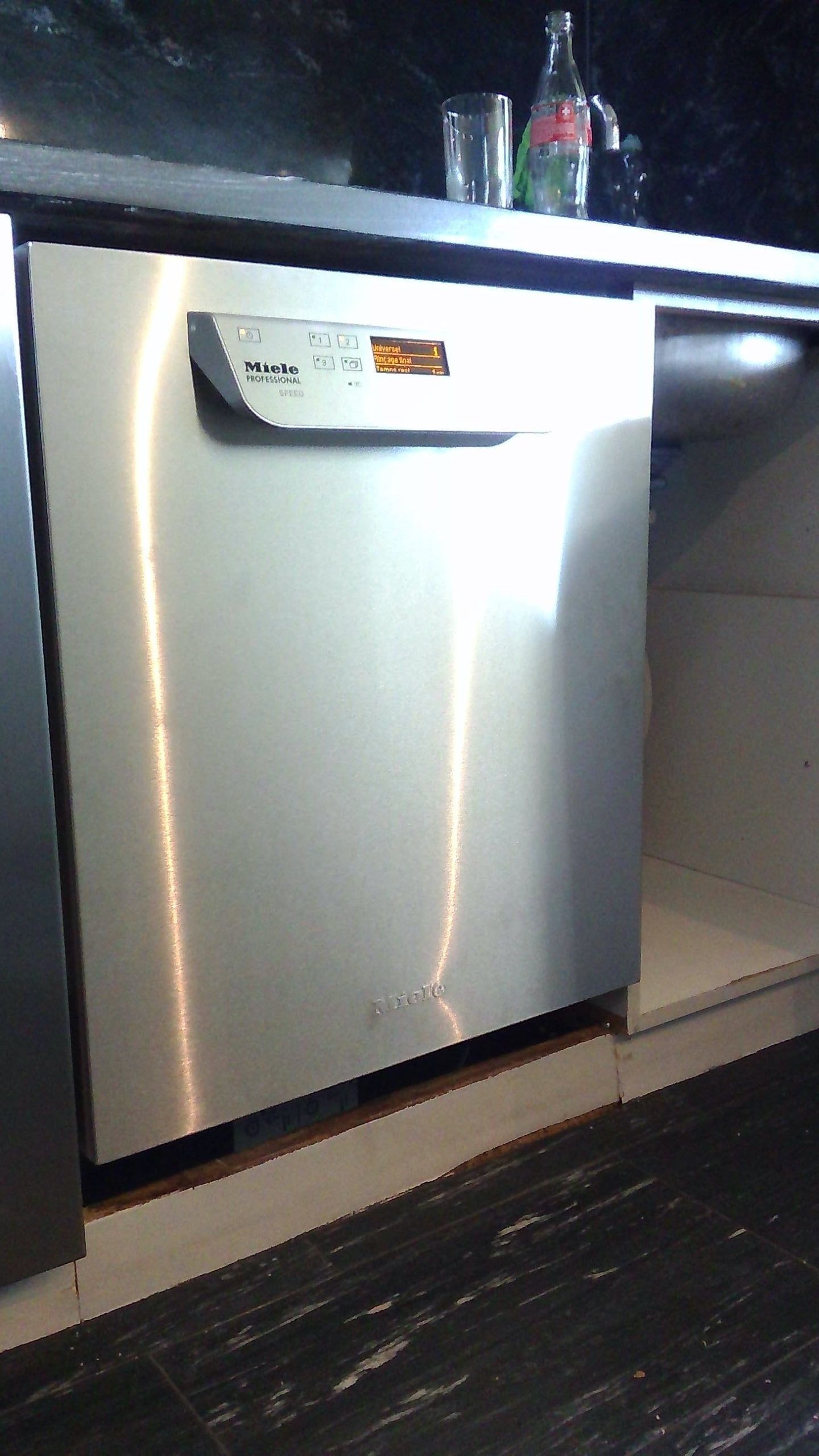 Porte d'électroménager en acier inoxydable, sur laquelle se reflète la lumière, à côté d'un placard blanc ouvert.