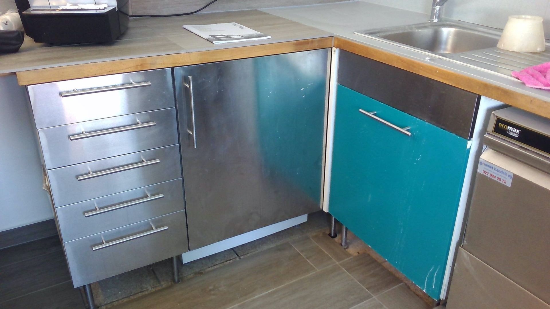 Armoires de cuisine en acier inoxydable avec comptoirs en bois ; porte accentuée turquoise.