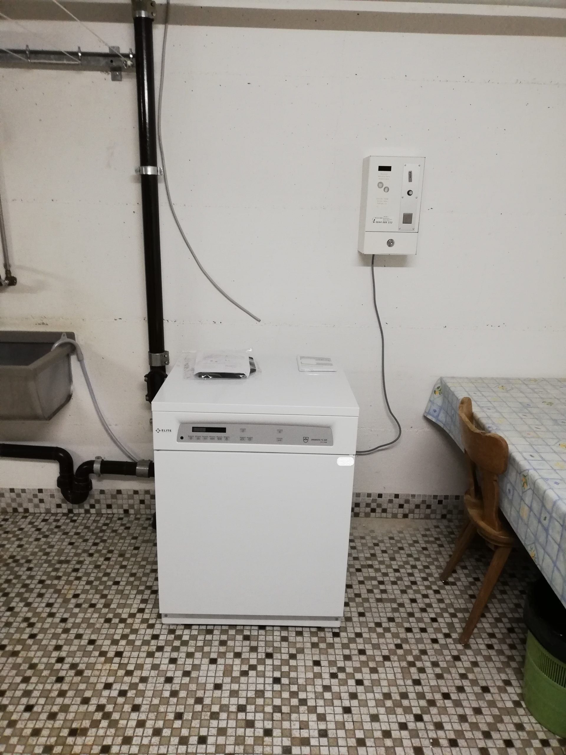 Lave-vaisselle blanc dans une pièce avec un évier et une table recouverte d'une nappe.