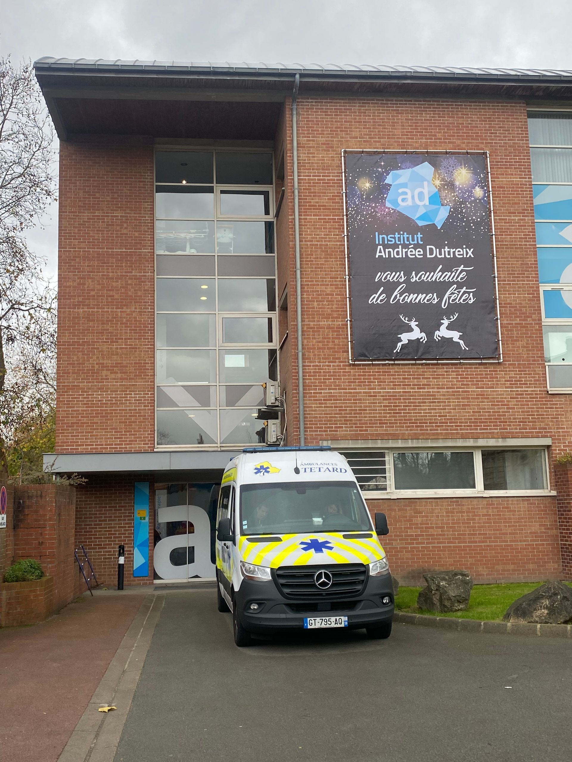 Une ambulance est garée devant l'entrée d'un bâtiment en briques.