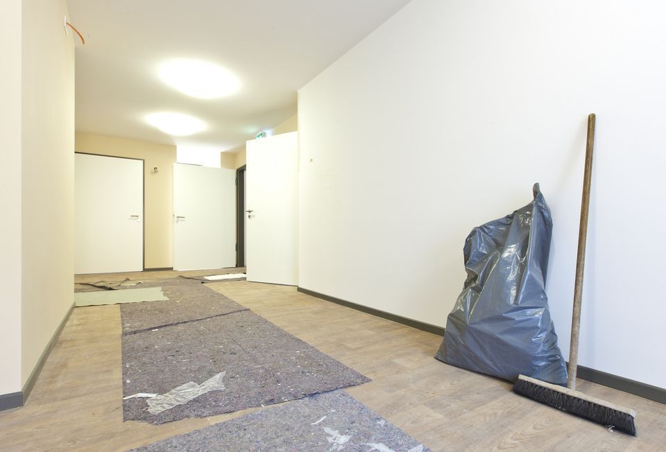 Ein Flur mit einem Besen und einem Müllsack auf dem Boden.