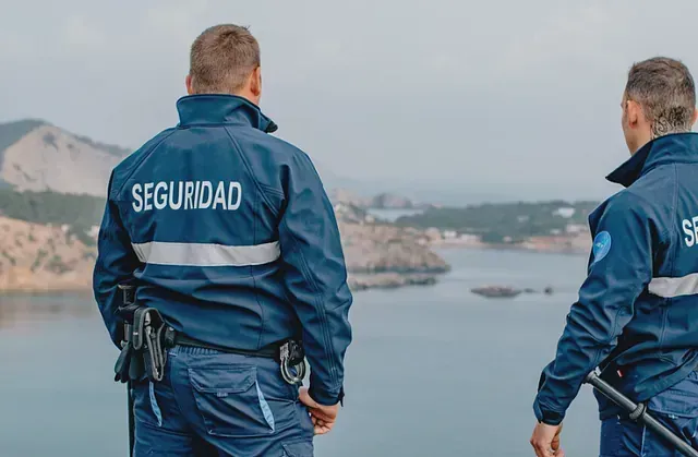 Dos guardias de seguridad están parados uno al lado del otro frente a un cuerpo de agua.