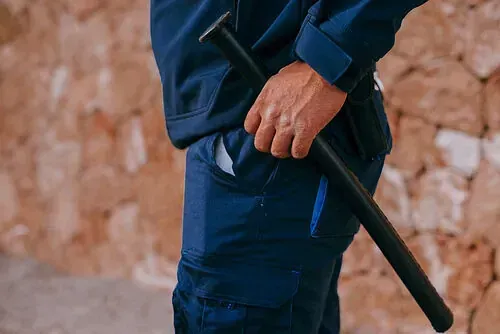 Un hombre con una chaqueta azul sostiene un bate en su bolsillo.