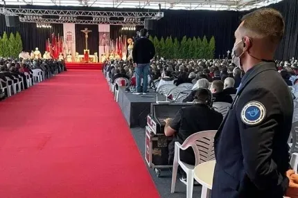 Un hombre que lleva una máscara está parado frente a una multitud de personas.