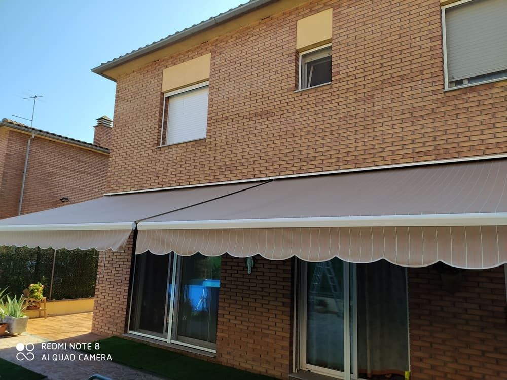 Una casa de ladrillo con un toldo blanco al costado.