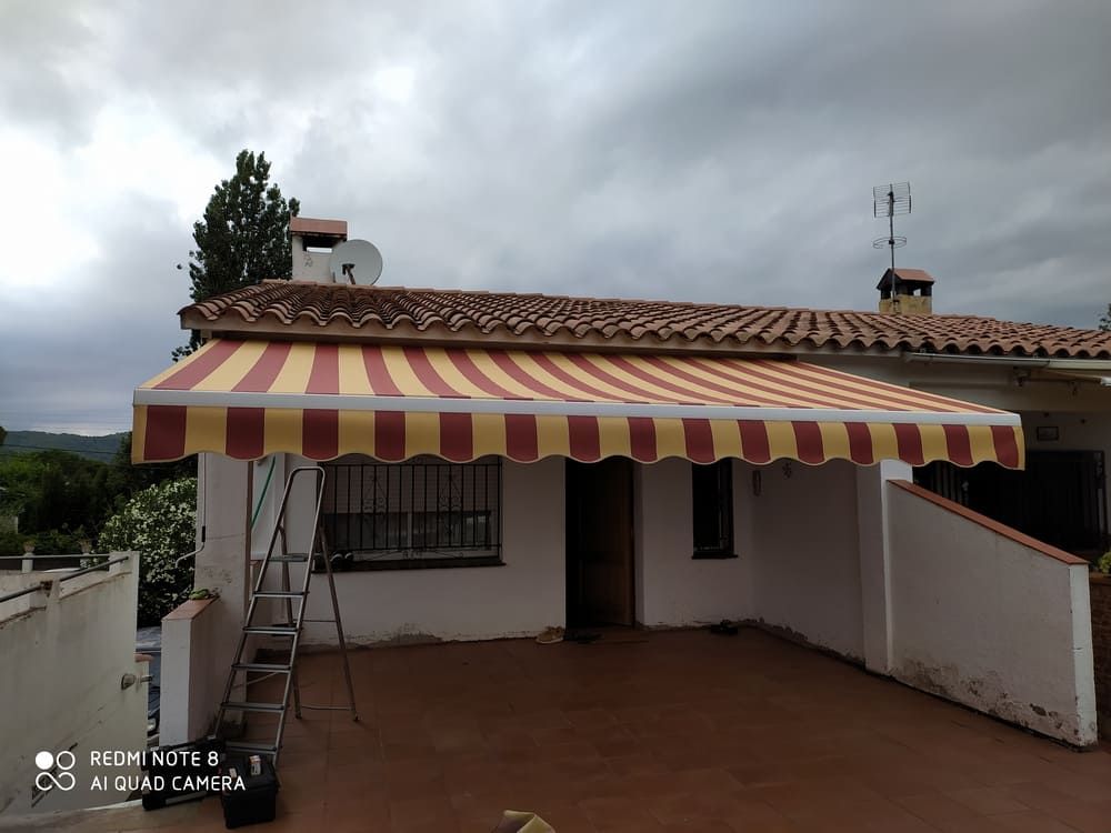 Un toldo de rayas rojas y amarillas está en el costado de una casa.