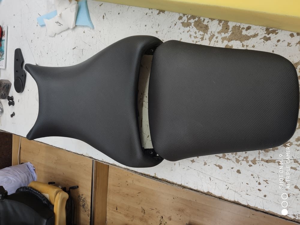 Un asiento de motocicleta negro está sobre una mesa de madera.