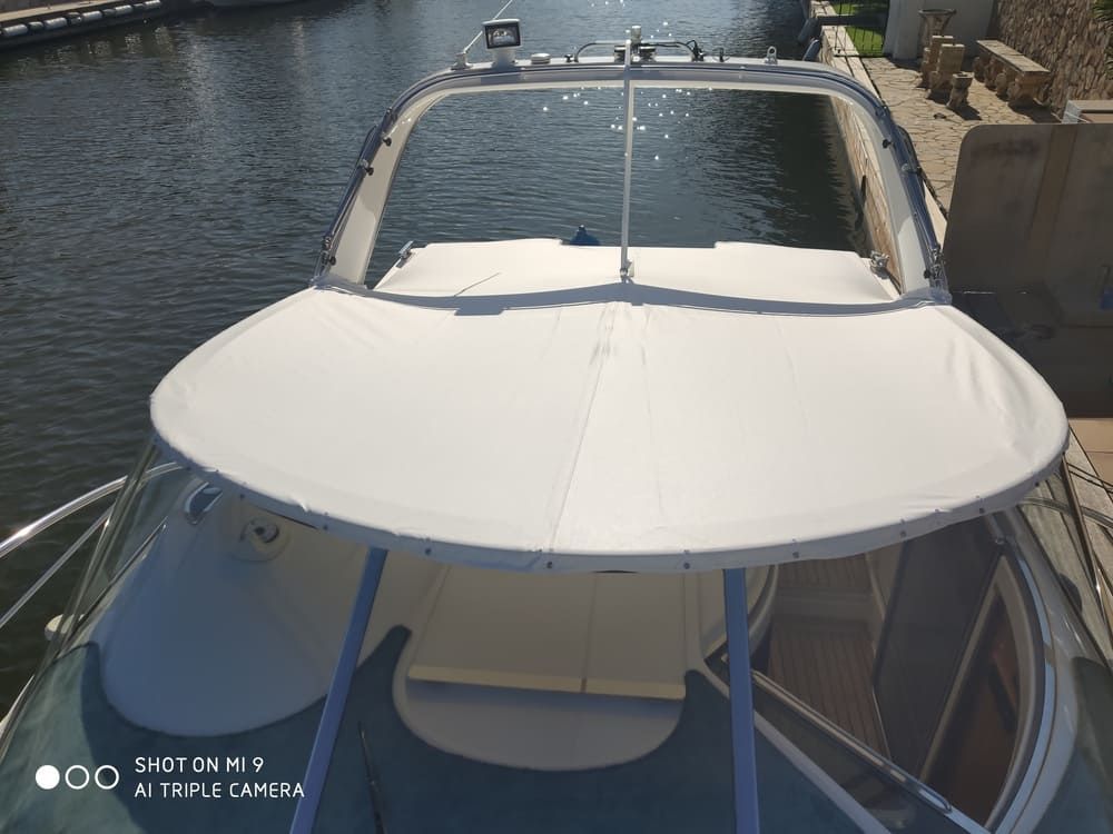 Un barco con un dosel blanco está atracado en el agua.