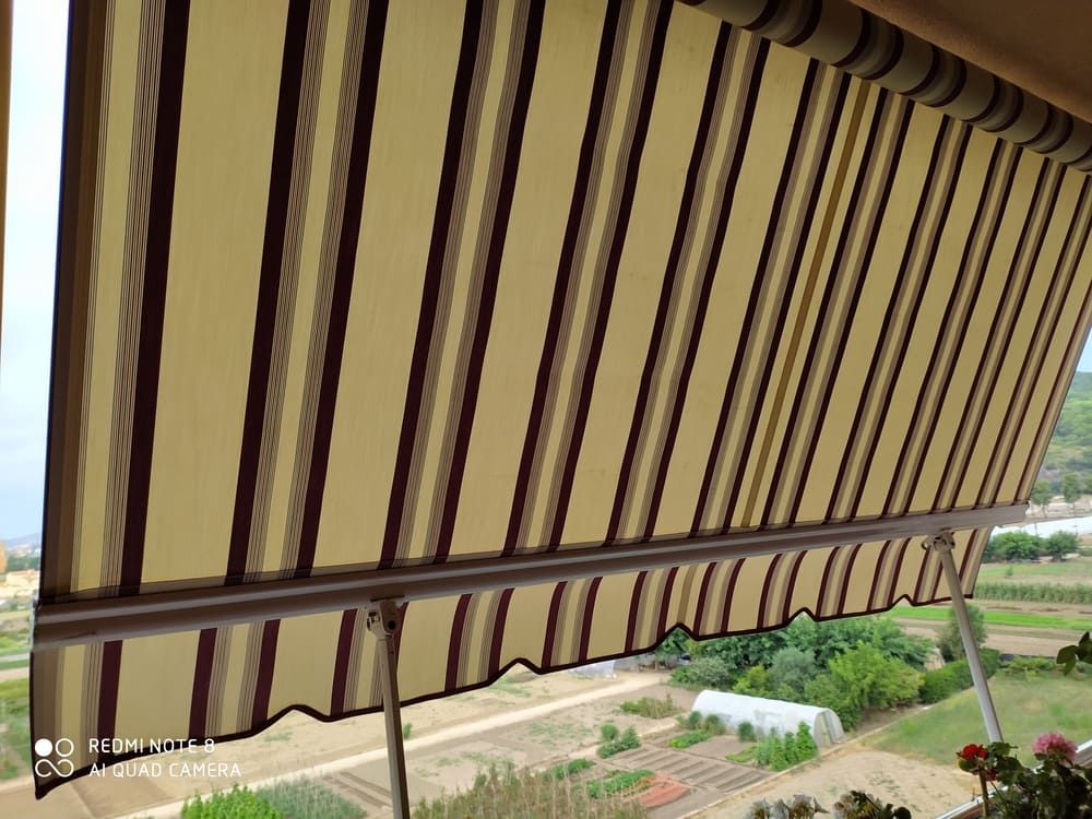 Un toldo a rayas cuelga de un balcón con vistas a un campo.