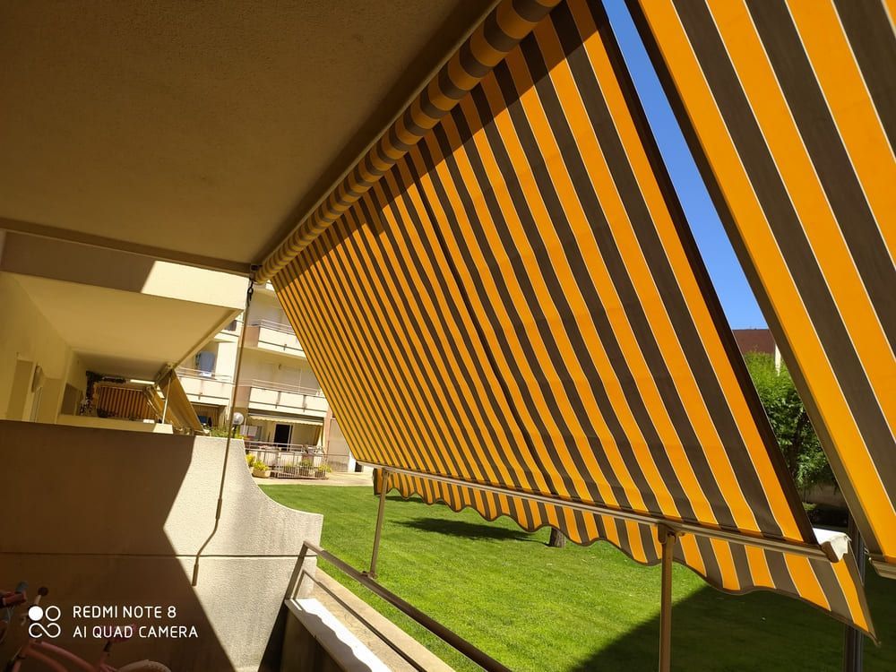 Un toldo de rayas amarillas y marrones cuelga sobre un balcón.