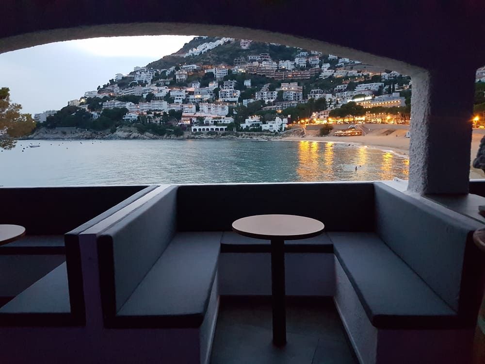 Un sofá con una mesa frente a una ventana con vista a un cuerpo de agua.