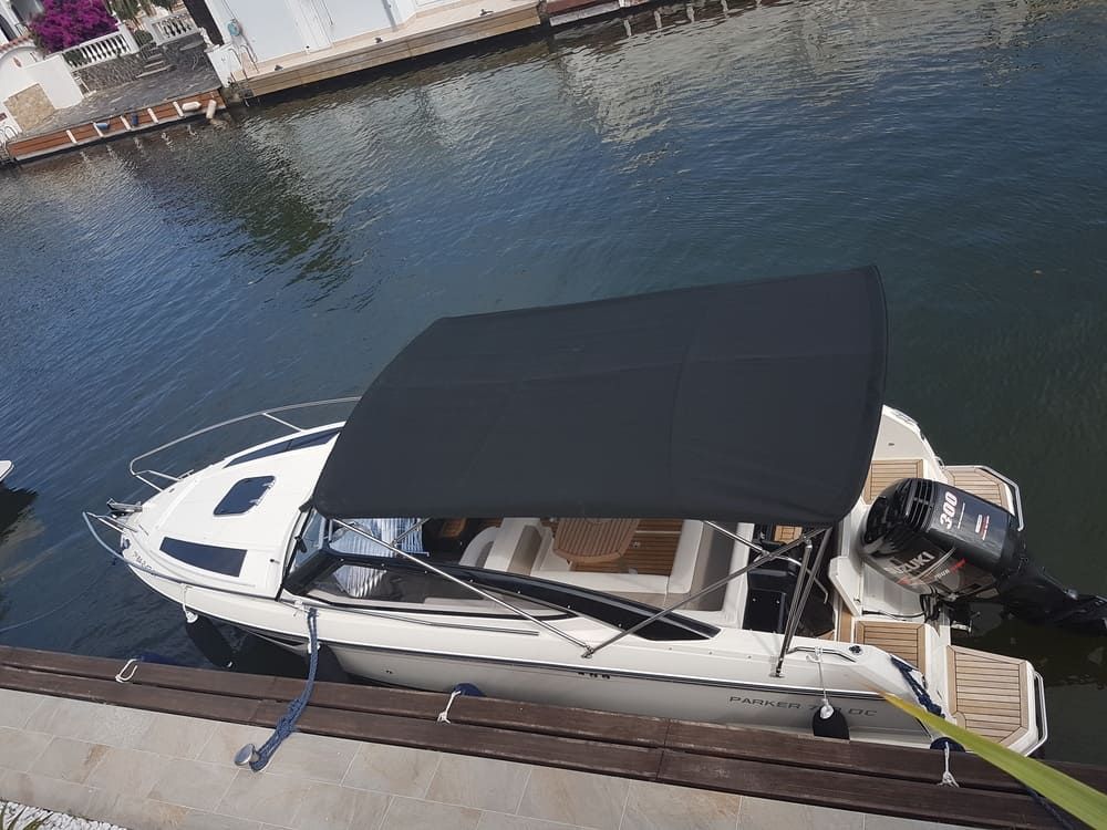 Un barco con un toldo negro está atracado en un muelle.