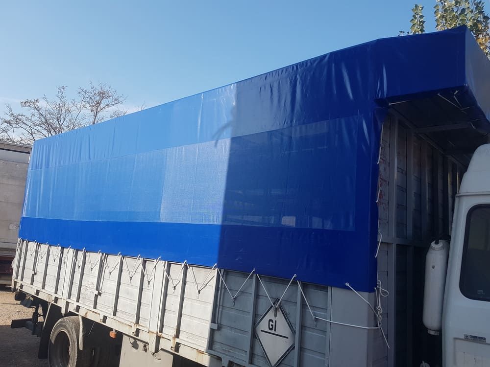 Un camión con una lona azul encima.