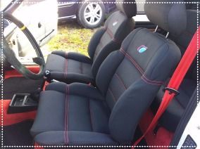 Un coche con asientos negros y cinturón de seguridad rojo