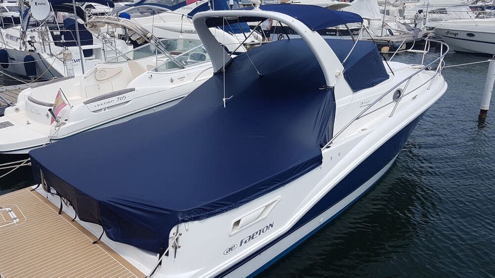 Un barco con cubierta azul está atracado en un puerto deportivo.