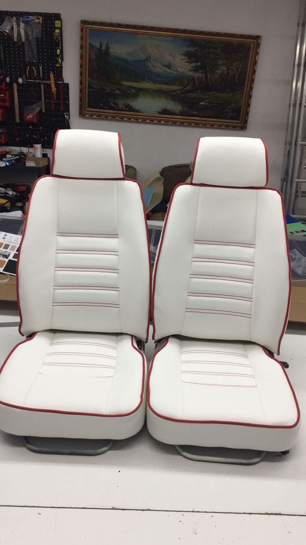 Un par de asientos de automóvil blancos con detalles rojos están sobre una mesa.
