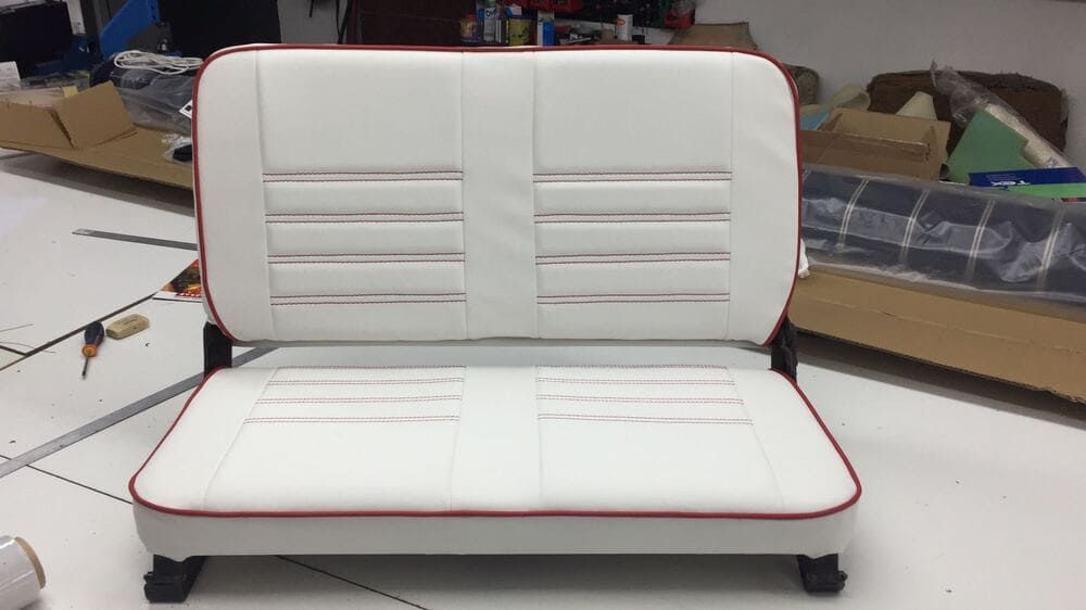 Un asiento de automóvil blanco con detalles rojos está sentado sobre un piso blanco.