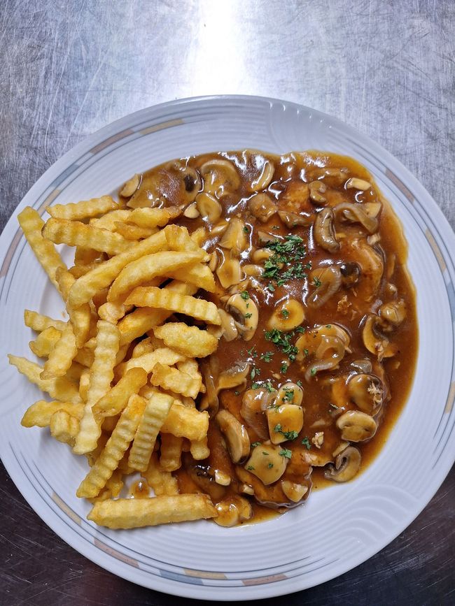 Gebratenes Hähnchen mit Pommes frites, gemischtem Gemüse und Dip-Sauce auf einem Teller.