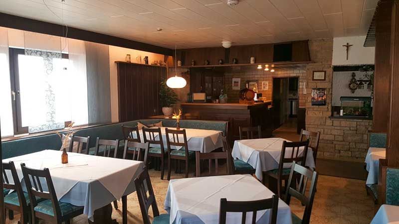 Restaurantinterieur mit Tischen, Stühlen, Bar und Fenstern.