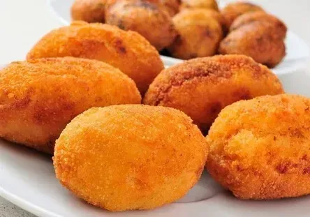 Alimentos fritos, empanizados y de color marrón dorado, dispuestos en platos blancos.