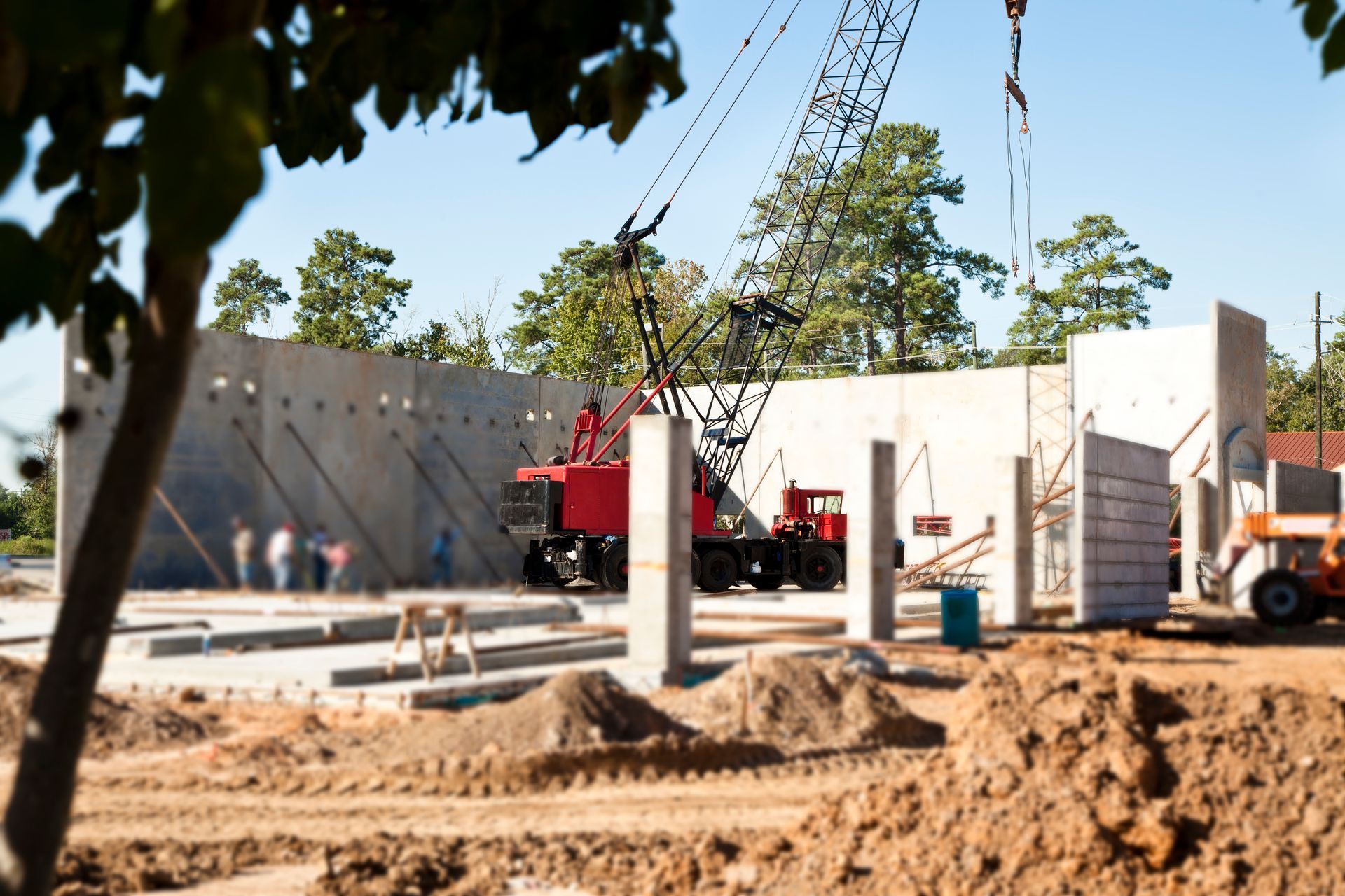 Obra en construcción con grúa elevando paneles de hormigón.