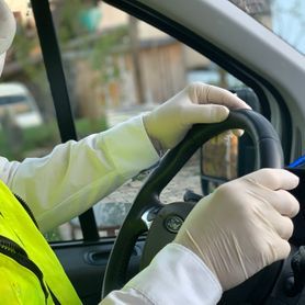 Person mit Gummihandschuhen und Mundschutz am Steuer