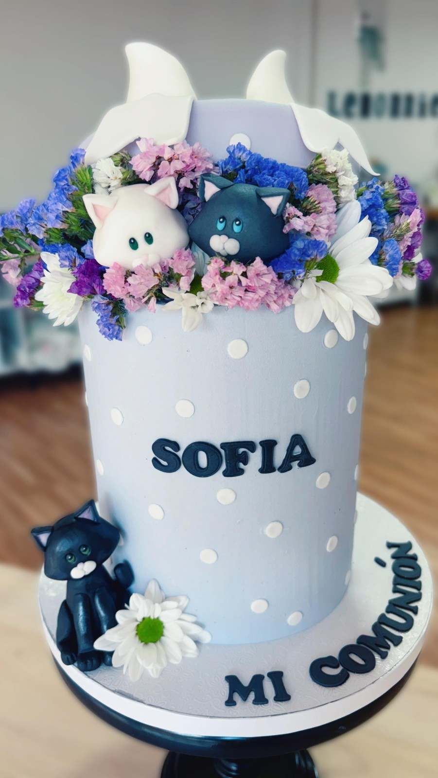 Taza blanca decorada con conejitos de peluche, flores y el nombre SOFIA sobre una base pequeña que dice MI COMUNIÓN