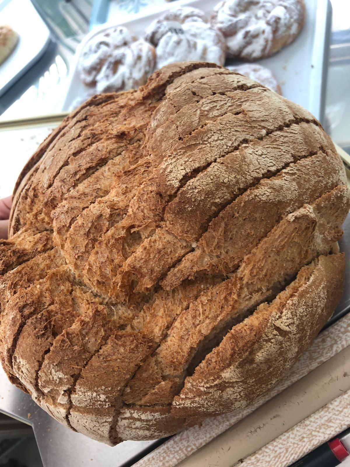 Una hogaza de pan está sobre una mesa al lado de una bandeja de donas.
