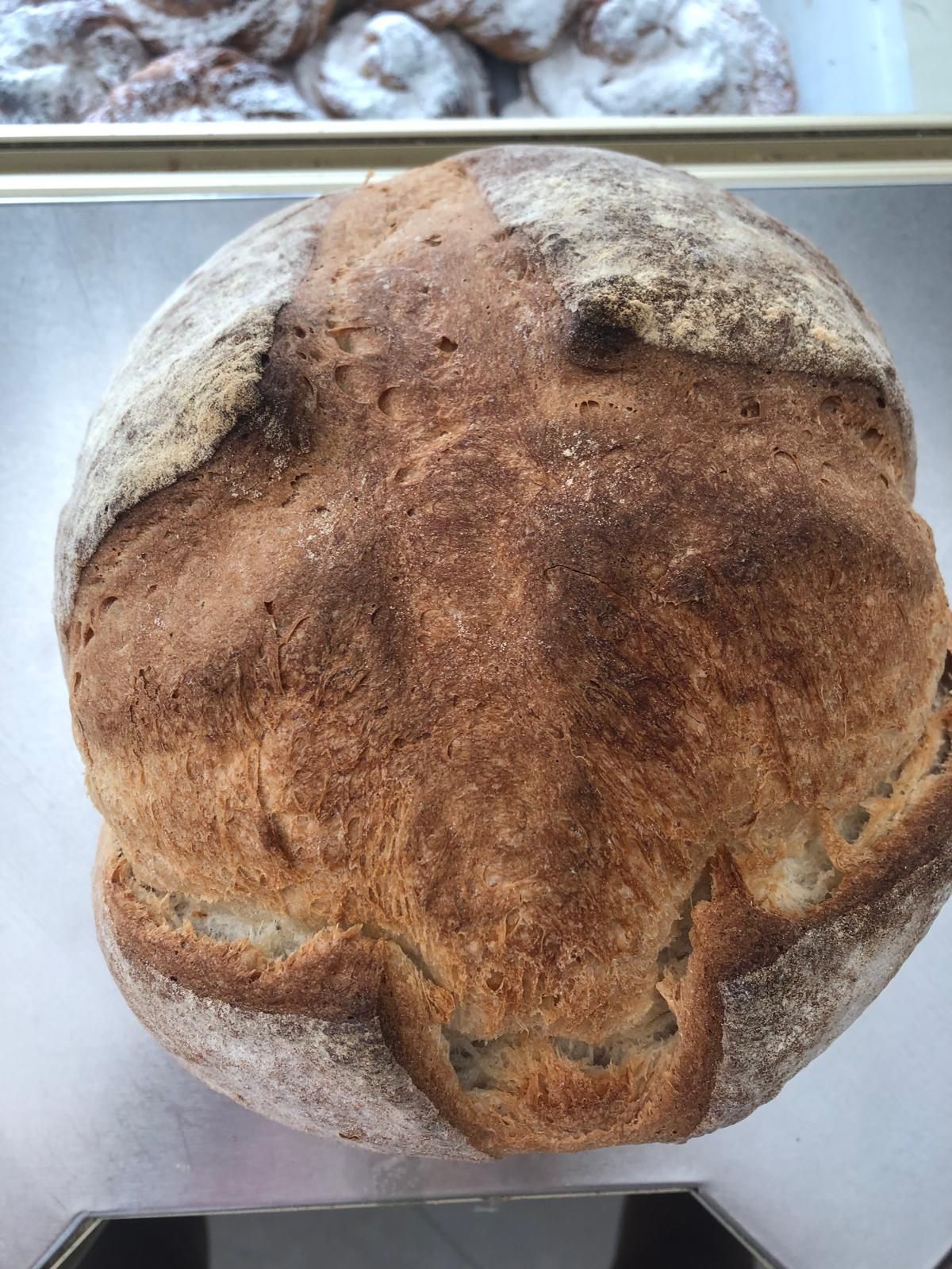 Una hogaza de pan reposa sobre una bandeja de metal.