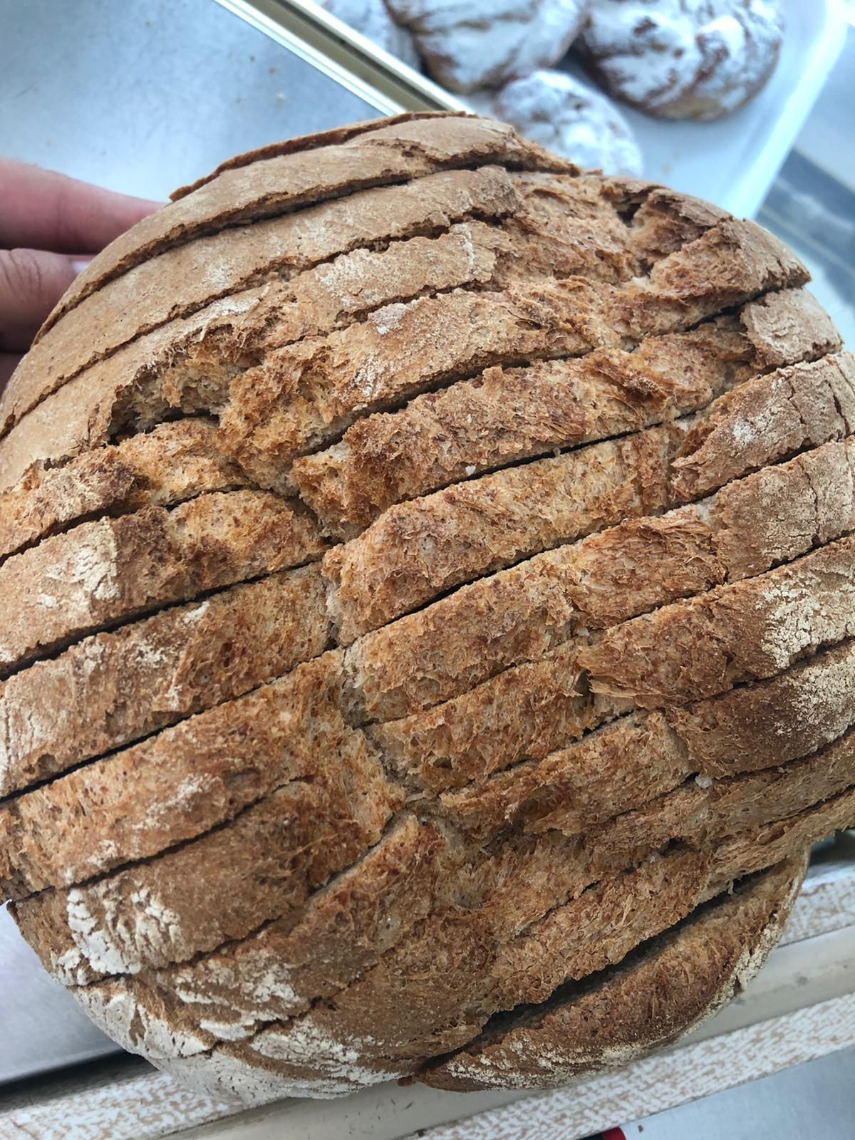 Una persona sostiene una hogaza de pan cortada en rebanadas.