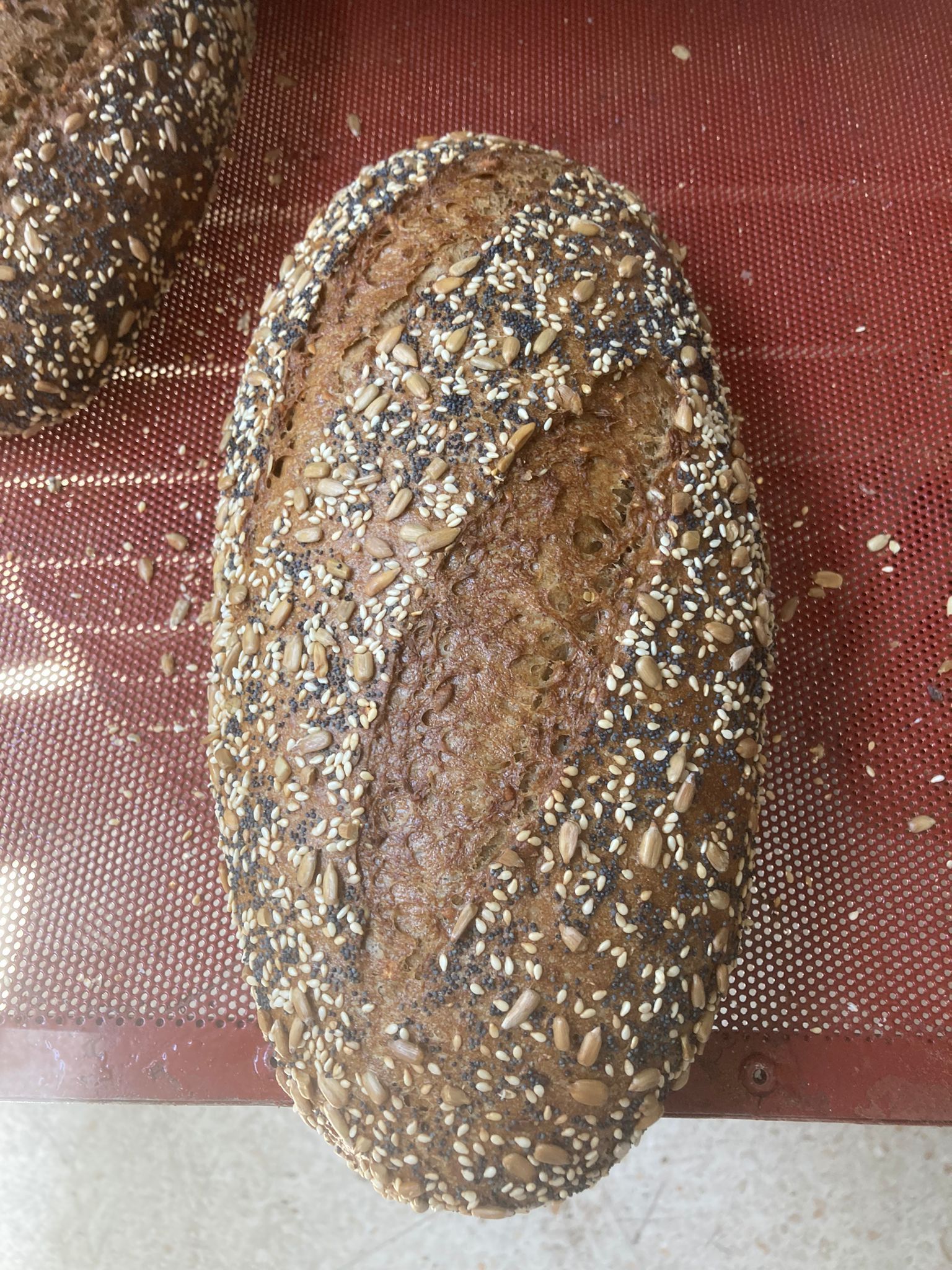 Una hogaza de pan con semillas está sobre una mesa.