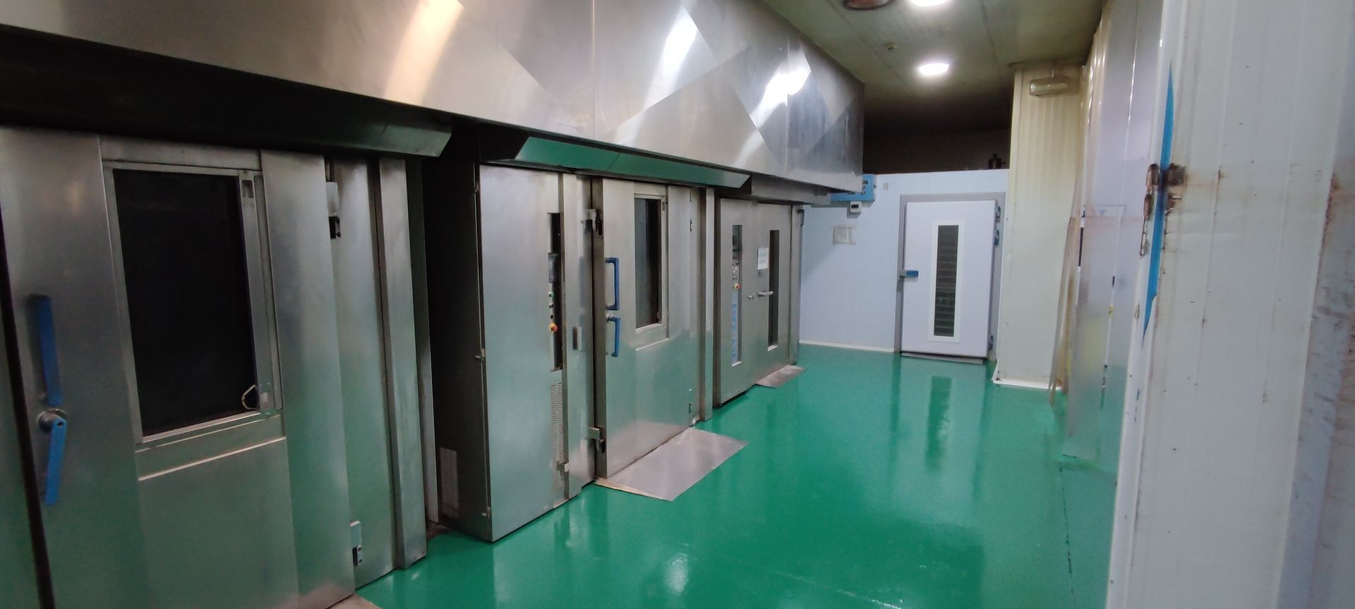 Una fila de hornos de acero inoxidable en una habitación con suelo verde.