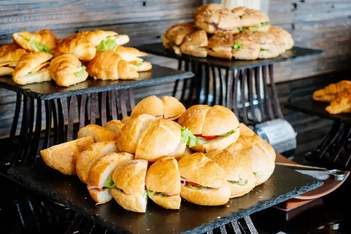 Variedad de panes precocidos presentados en bandejas de pizarra para eventos de restauración.