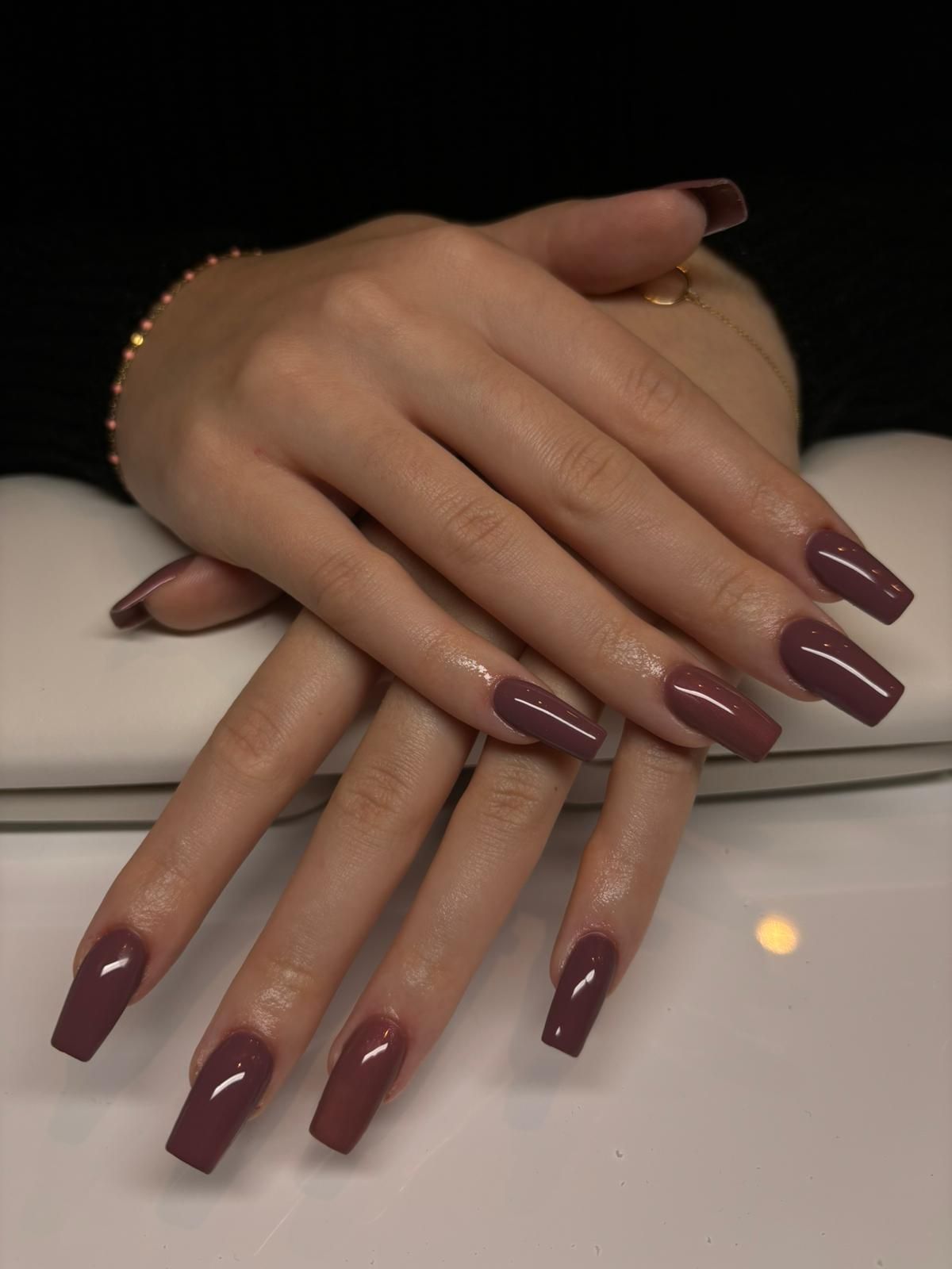 Ongles longs taillés en carré avec gel et vernis rouge prononcé couleur bordeaux
