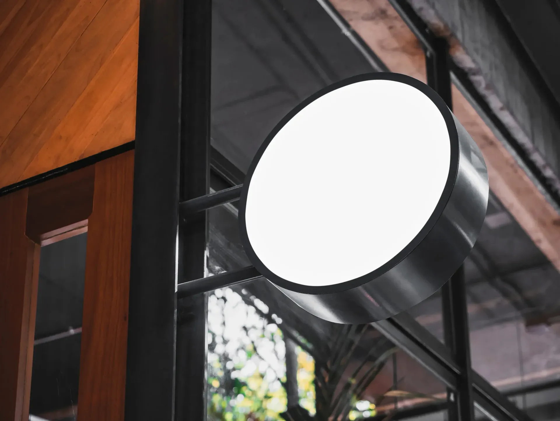 Letrero circular blanco para escaparate. Marco plateado, cara blanca, montado sobre un poste negro.