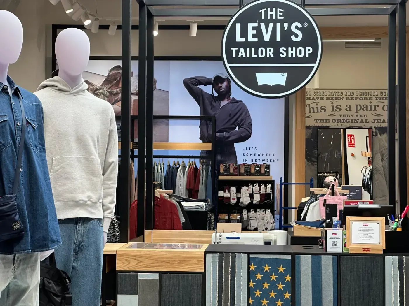 Levi's Tailor Shop en una tienda: maniquíes al frente, cartel encima de la tienda, exhibición de ropa en el interior.
