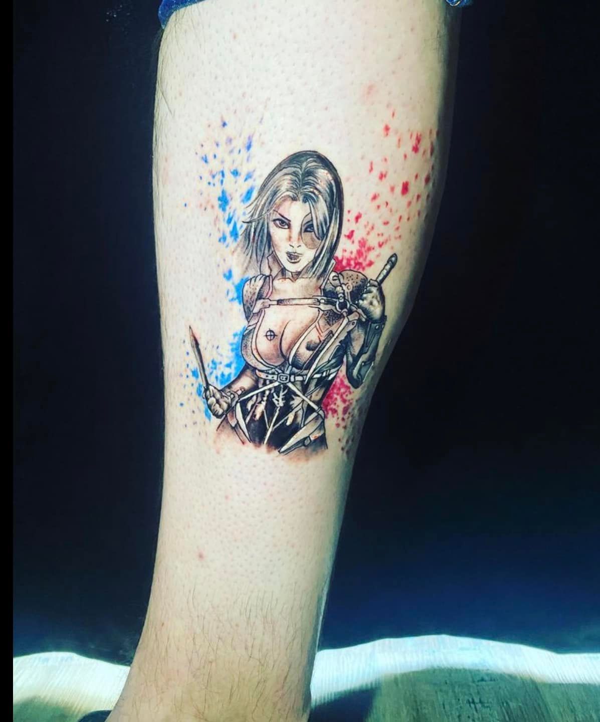 Tatouage représentant une femme avec des éclaboussures bleues et rouges
