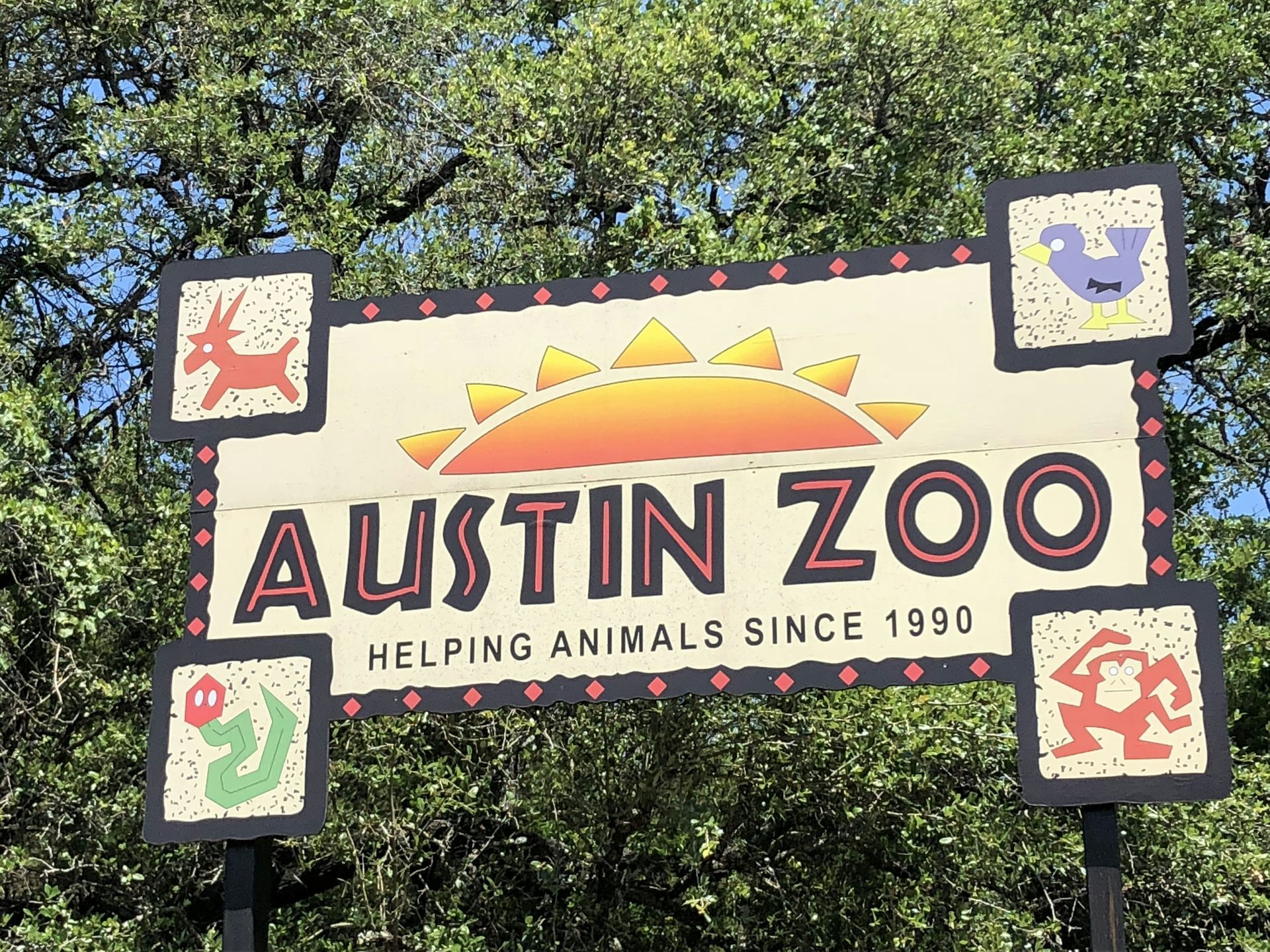 Austin Zoo sign with a sun graphic and animal icons. 