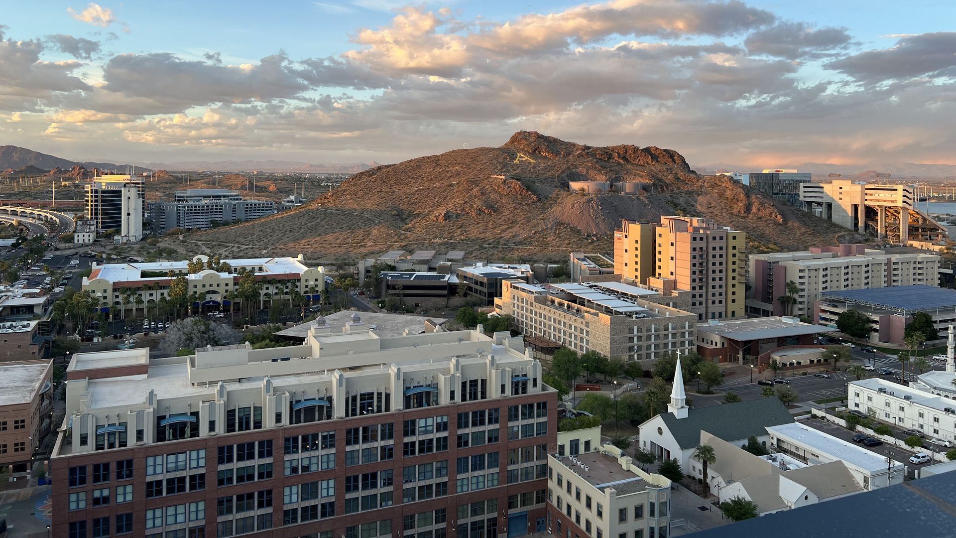 Cityscape with mountain background and cloudy sunset. Buildings in the foreground.