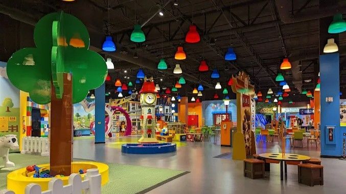 Colorful children's play area with tree, various play structures, and hanging lights.