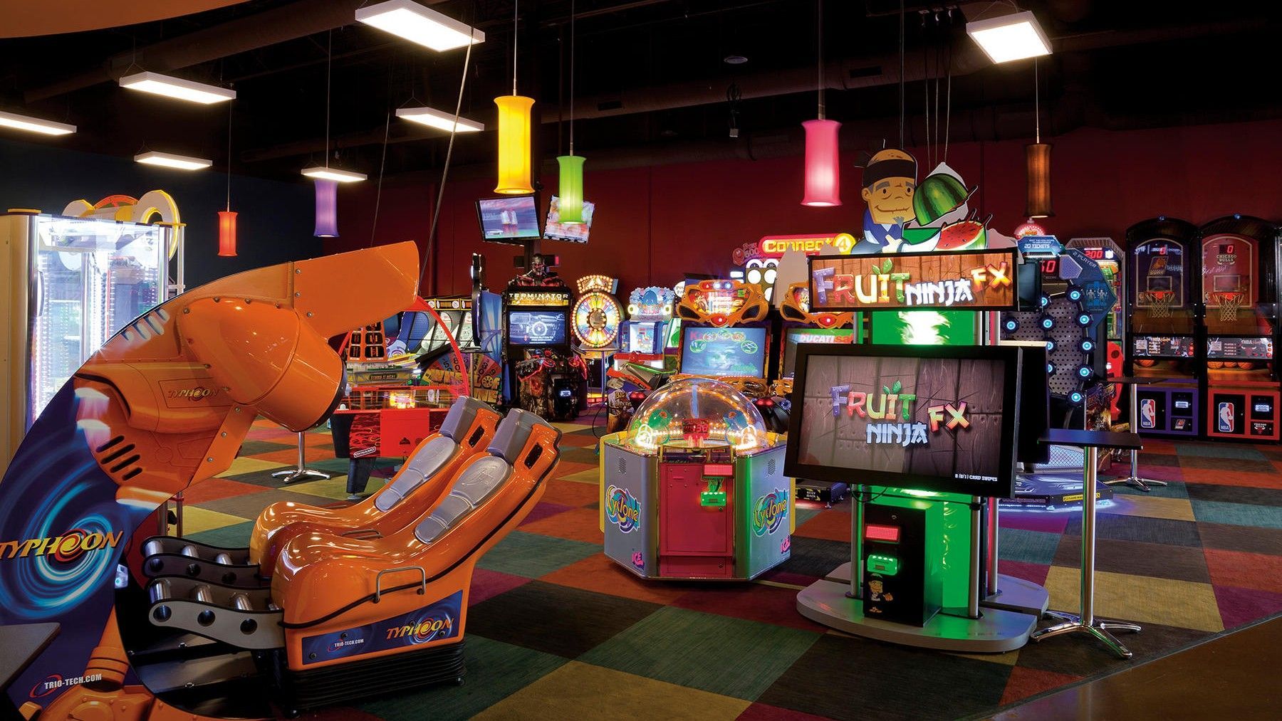Arcade room with various game machines. Brightly lit, colorful environment.