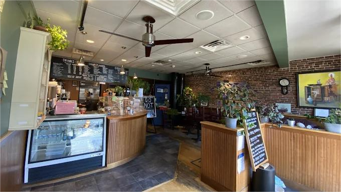 Interior view of a coffee shop with a counter, brick wall, and ceiling fans.