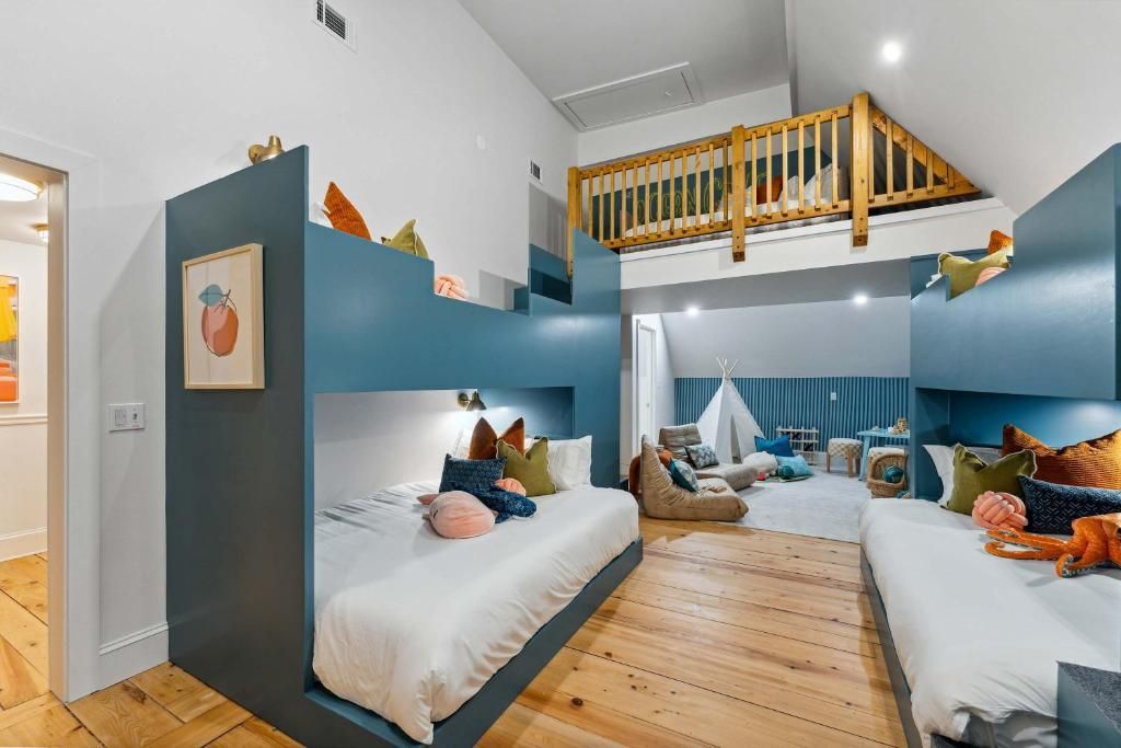 Bright shared bedroom with blue walls, bunk bed, and twin beds around a large window seat area