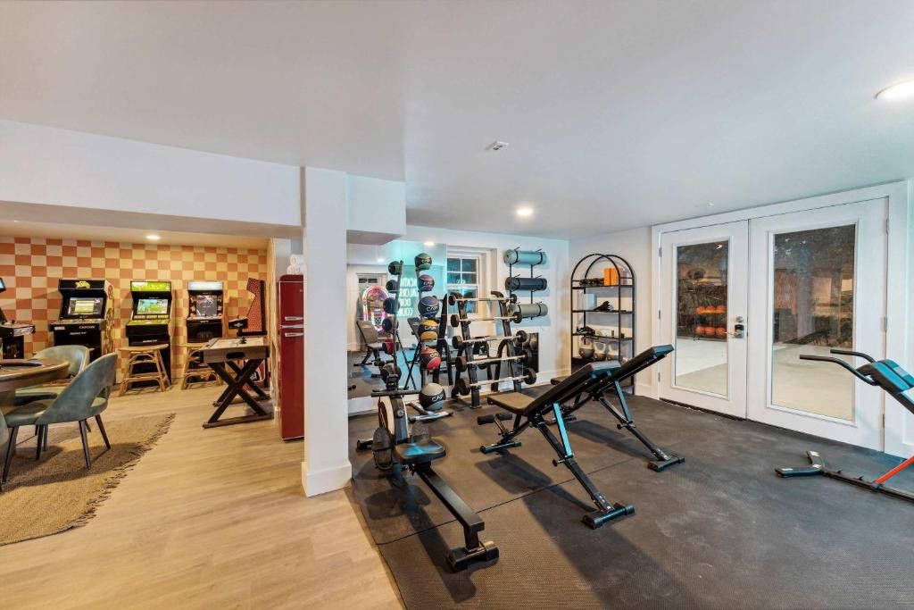 Modern home gym with exercise equipment, mirrors, and light wood flooring in an open basement room