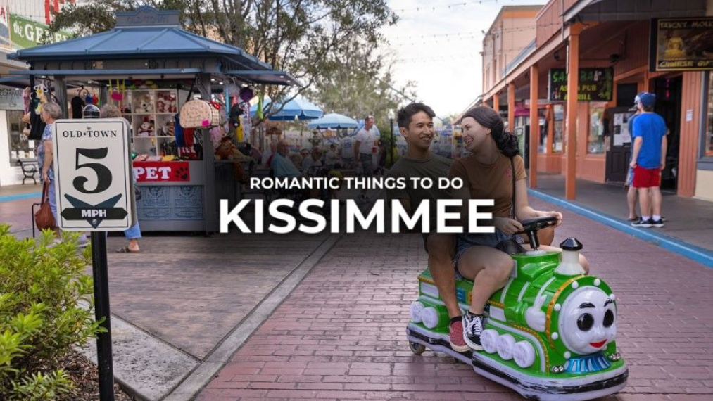Couple riding a green toy train in Kissimmee, Florida. Sign for