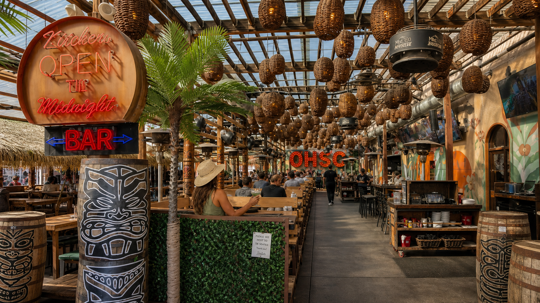 Outdoor bar and restaurant with tiki decor, hanging lights, and a central walkway lined with tables and stools