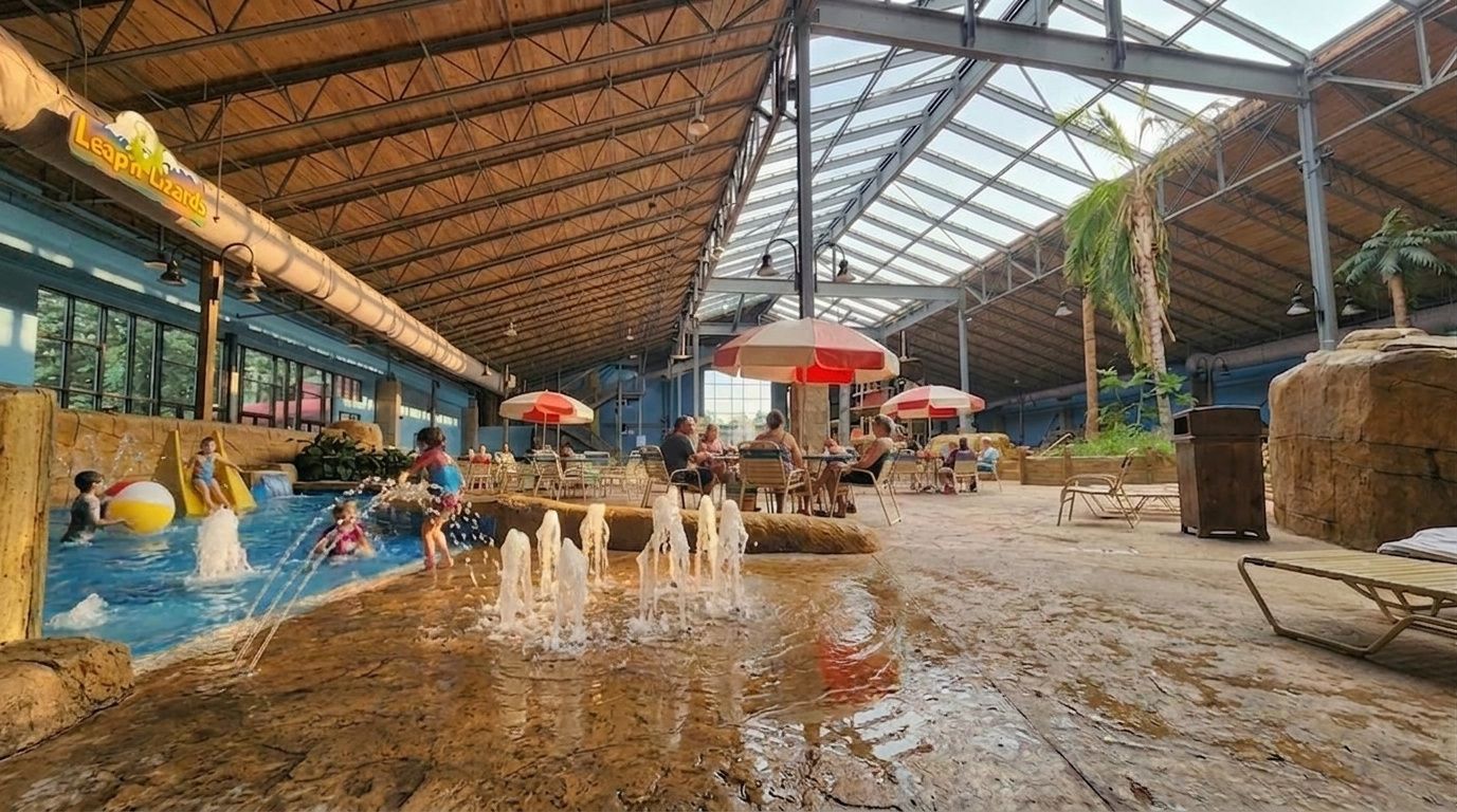 Indoor water park with children wading in a shallow pool under a large open roof