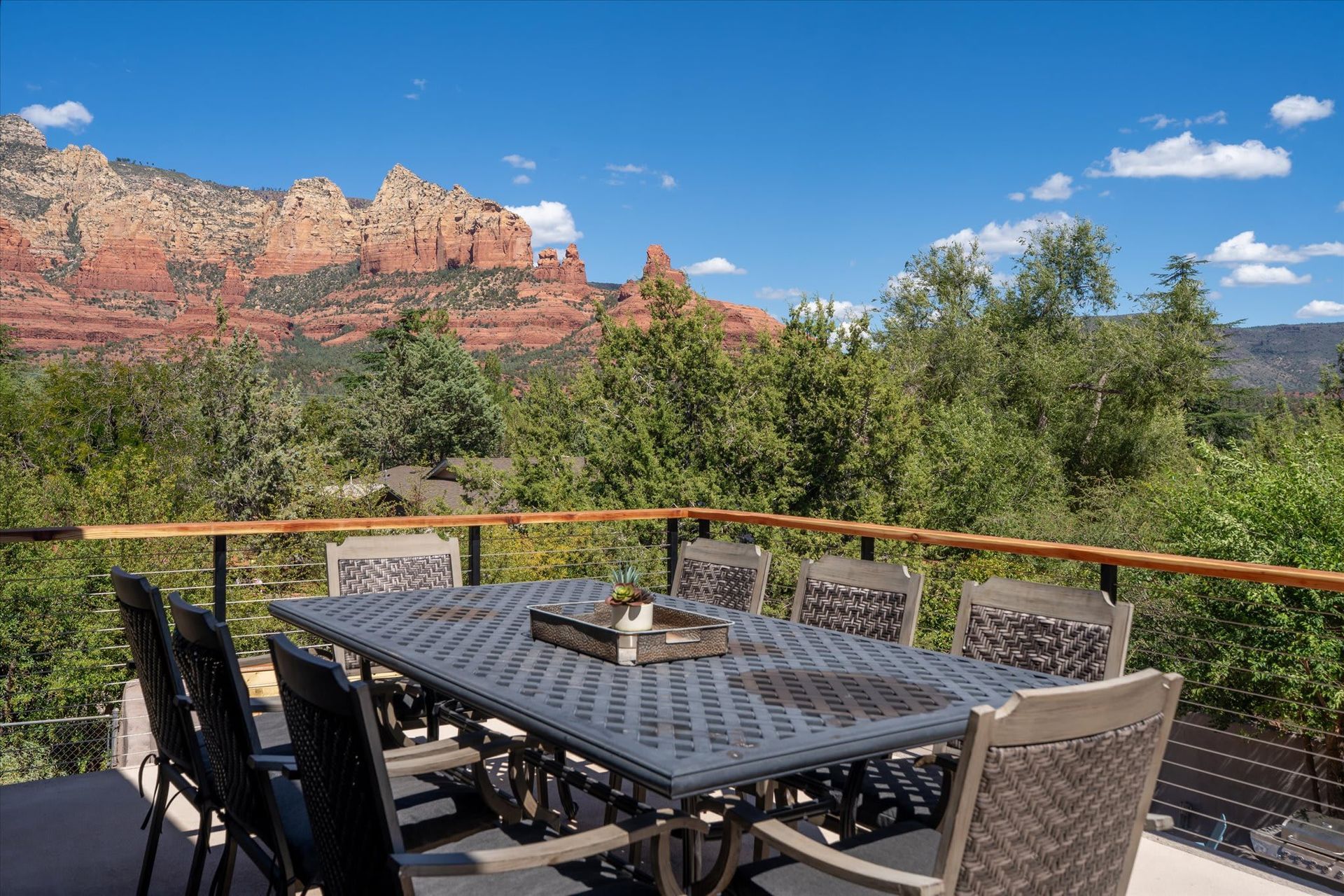 Patio table and chairs overlooking red rock cliffs and blue sky on a sunny day